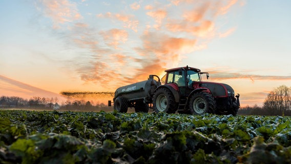 Ein Traktor fährt Gülle auf ein Ackerfeld. © imago Foto: Marius Schwarz