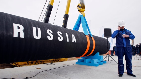 Ein russischer Bauarbeiter telefoniert neben einem Rohrstück für die Gas-Pipeline Nord Stream (Portowaja). © dpa Foto: Dmitry Lovetsky