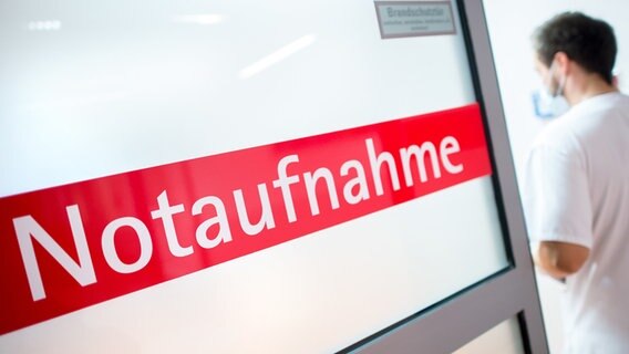 Eine Tür mit der roten Aufschrift "Notaufnahme" ist leicht geöffnet. Hinter ihr steht ein Mitarbeiter der Klinik. © dpa picture alliance Foto: Hauke-Christian Dittrich