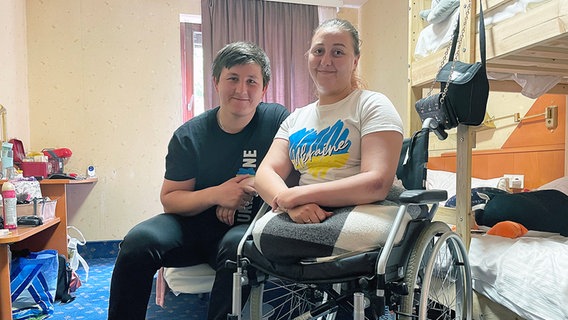 Oksana im Rollstuhl ohne Beinprothesen, daneben ihr Mann. © NDR 