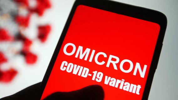The text is on the screen of a smartphone "Omicron COVID-19-variant" to read. (Symbol photo) © dpa-Bildfunk