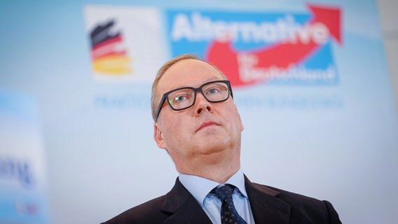 CDU-Mitglied Max Otte steht vor einem Partei-Logo der AfD. © Kay Nietfeld/dpa 