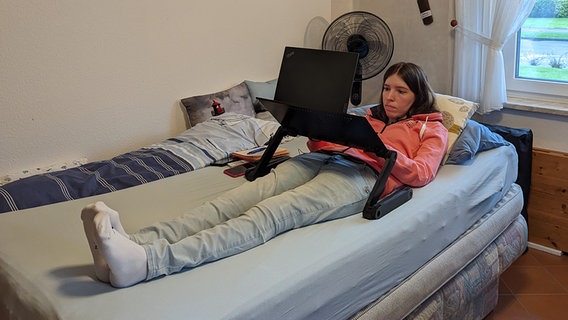 Elke Paatz, Inklusionsbeauftragte des Deutschen Seglerverbands, liegt auf einem Bett und arbeitet am Laptop. © NDR Foto: Astrid Kühn