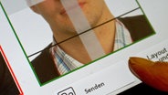 Ein digital aufgenommenes biometrisches Lichtbild wird auf einem Endgerät zur elektronisch verschlüsselten Übermittlung über eine sichere Verbindung via De-Mail angezeigt. © Swen Pförtner/dpa 