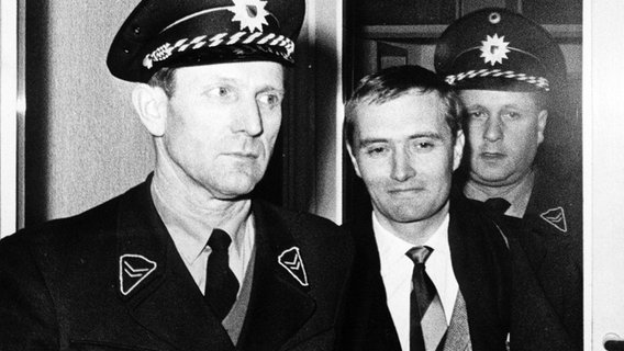 Polizisten geleiten "Spiegel"-Herausgeber Rudolf Augstein 1963 ins Gerichstgebäude in Karlsruhe. © picture alliance / Associated Press FILES | LINDLAR 