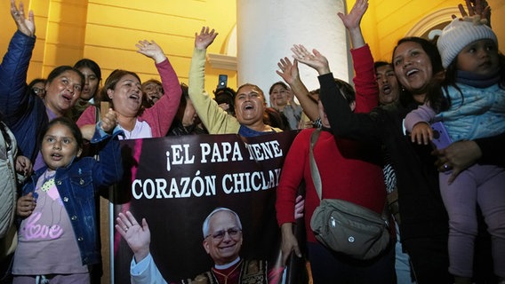 Peru, Chiclayo: Gemeindemitglieder halten ein Foto von Bischof Robert Prevost, der zum Papst Leo XIV. gewählt wurde, nach der Messe in der Kathedrale von Chiclayo, wo er mehrere Jahre lang als Bischof diente. © Guadalupe Pardo/AP/dpa 