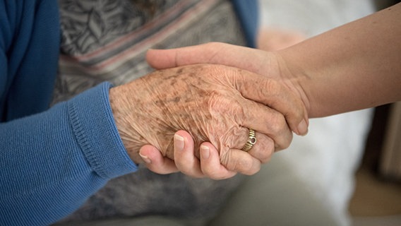 Eine Pflegefachkraft hält die Hand einer Pflegeheim-Bewohnerin © picture alliance/dpa | Sina Schuldt Foto:  Sina Schuldt