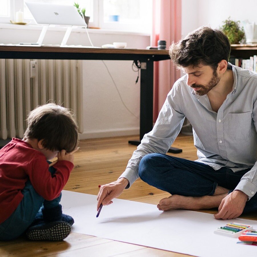 Ein Mann sitzt neben seinem Sohn auf dem Boden des Zimmers © Marcus Heep Foto: Marcus Heep