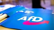 Fähnchen mit dem Logo der AfD liegen auf einem Tisch. © dpa Foto: Daniel Karmann