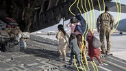 Eine Familie aus Afghanistan boardet ein Flugzeugzeug während einer Evakuierungsaktion im August 2021. © picture alliance 
