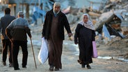 Menschen gehen an zerstörten Gebäuden im Flüchtlingslager Al-Maghazi im Zentrum des Gazastreifens im Zentrum des Gazastreifens vorbei. © dpa Foto: XinHua