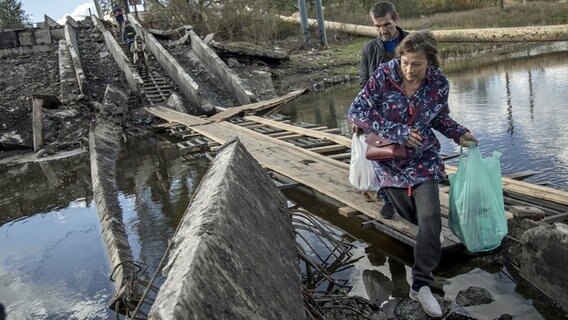 Zivilisten gehen über eine eingestürzte Brücke in der Innenstadt von Bachmut (Ukraine, Donezk). © Anadolu Agency Foto: Narciso Contreras