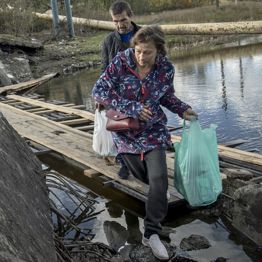 Zivilisten gehen über eine eingestürzte Brücke in der Innenstadt von Bachmut (Ukraine, Donezk). © Anadolu Agency Foto: Narciso Contreras