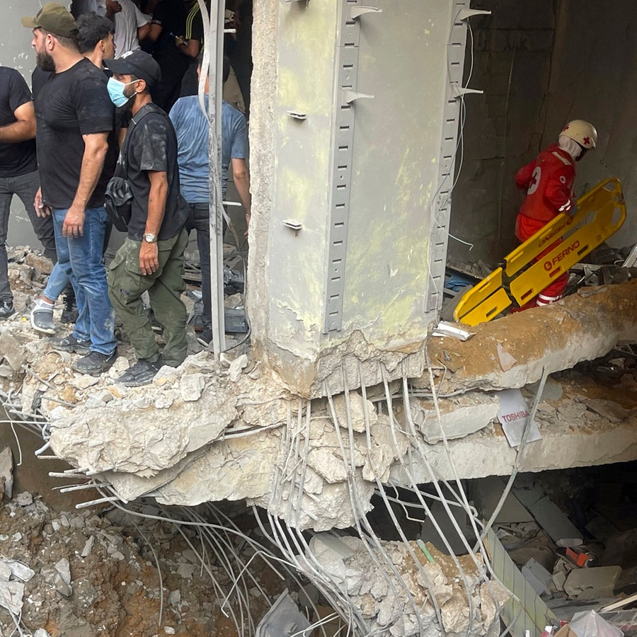 Menschen und Rettungskräfte versammeln sich am Ort eines israelischen Raketeneinschlags in den südlichen Vororten von Beirut (Libanon). © AP Foto: Bilal Hussein