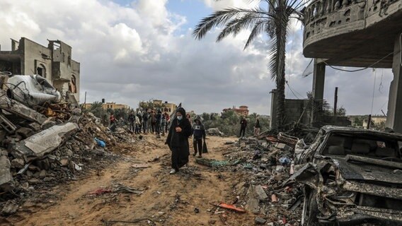 Palästinenser gehen durch die Überreste zerstörter Gebäude nach israelischem Bombardement in Rafah (Süd-Gaza). © dpa Foto: Abed Rahim Khatib