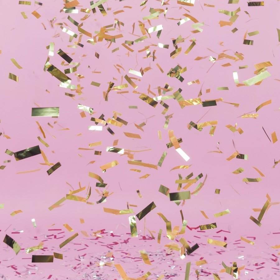 Glänzendes goldenes Konfetti fällt herab auf einem rosa Hintergrund © Zoonar Foto: Oleksandr Latkun