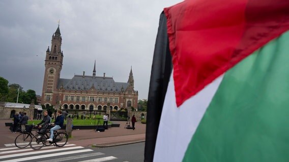 Ein Demonstrant schwenkt die palästinensische Fahne vor dem Friedenspalast in Den Haag (Niederlande), in dem der "Internationale Gerichtshof der Vereinten Nationen" untergebracht ist. © AP/dpa Foto: Peter Dejong