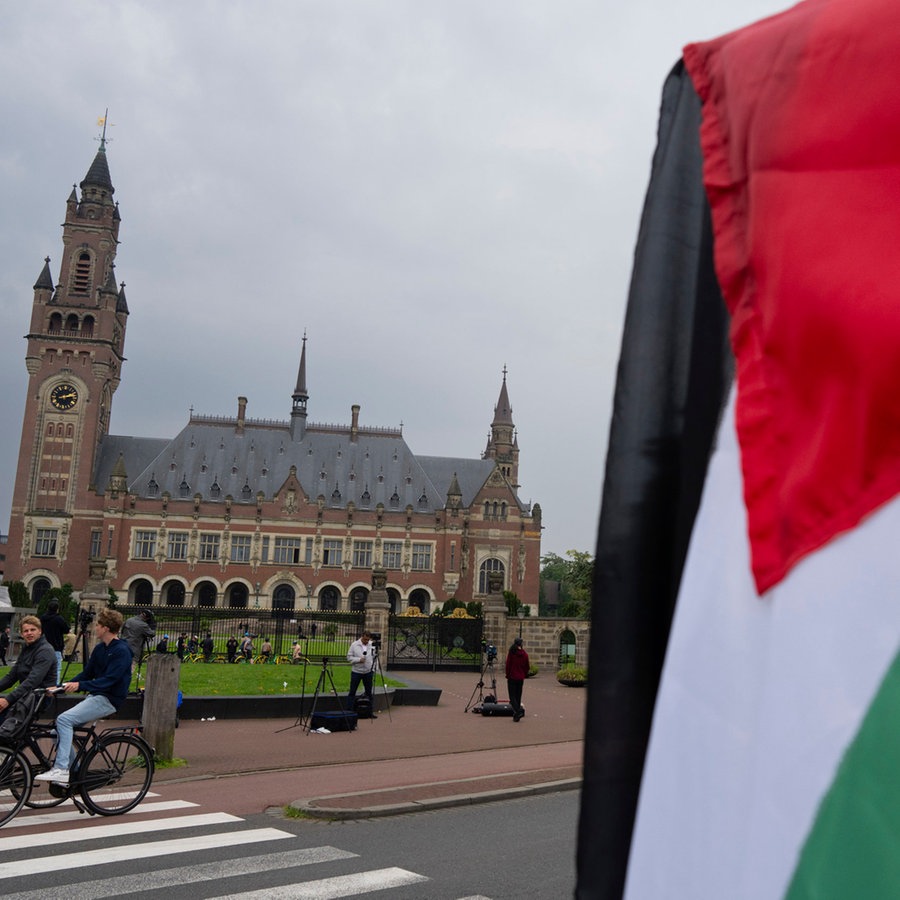 Ein Demonstrant schwenkt die palästinensische Fahne vor dem Friedenspalast in Den Haag (Niederlande), in dem der "Internationale Gerichtshof der Vereinten Nationen" untergebracht ist. © AP/dpa Foto: Peter Dejong