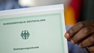 Ein Mann aus Afrika hält seine Einbürgerungsurkunde der Bundesrepublik Deutschland in der Hand. © dpa Foto: Julian Stratenschulte