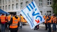 Mitglieder der Eisenbahn- und Verkehrsgewerkschaft (EVG) nehmen an einer Kundgebung teil und schwenken Fahnen. © picture alliance / dpa Foto: Lukas Schulze