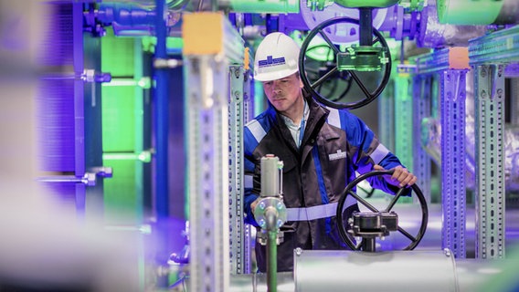Ein Arbeiter bedient die Geothermieanlage der Stadtwerke Schwerin in der mit farbigem Licht illuminierten Anlage der Wärmetauscher. © dpa-Bildfunk Foto: Jens Büttner