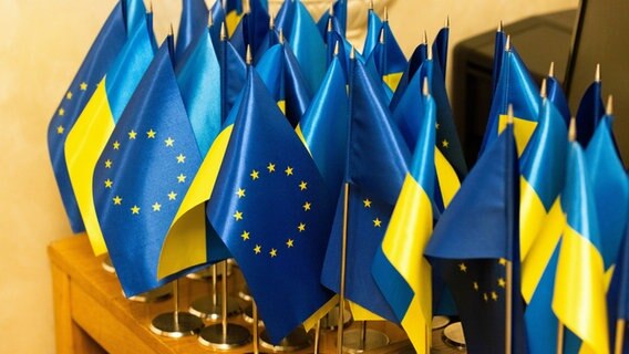 Kleine ukrainische und europäische Flaggen sind auf einem Tisch zu sehen, beim Besuch von der Präsidentin der Europäischen Kommission, Ursula von der Leyen, in Kiew (Ukraine). © dpa-ENR-Pool/dpa Foto: Philipp von Ditfurth
