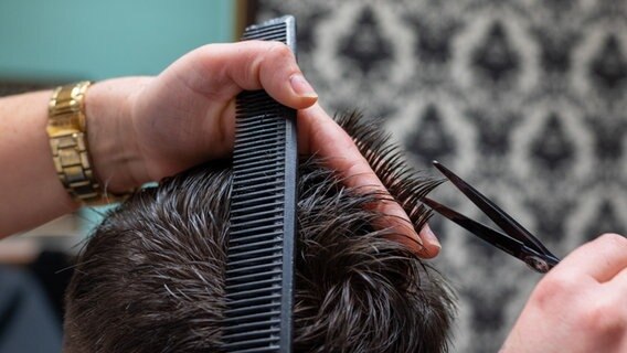 Eine Friseurin schneidet einem Mann die Haare © picture alliance/dpa | Armin Weigel Foto:  Armin Weigel