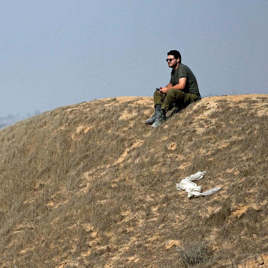 Ein israelischer Soldat sitzt auf einer Anhöhe nahe der Grenze zum Gazastreifen im Süden Israels. © AP/dpa Foto: Tsafrir Abayov