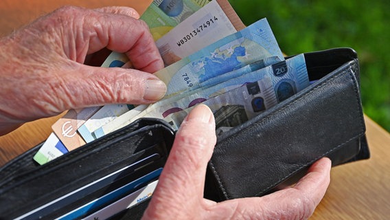 Zwei Hände halten einen geöffneten Geldbeutel und ziehen Geldscheine heraus © picture alliance / SvenSimon | Foto:  Frank Hoermann/SVEN SIMON