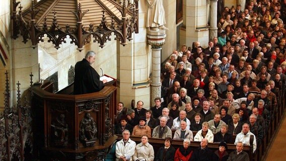 Ein Pfarrer predigt von der Kanzel in einer vollbesetzten Kirche. © picture-alliance / ZB | Thomas Schulze Foto: Thomas Schulze