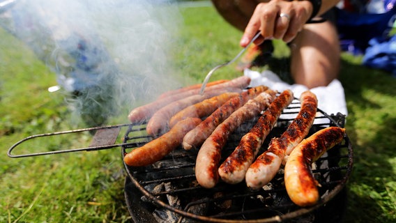 Im Park werden Würstchen auf einem Grill gegrillt. © picture alliance Foto: Ludovic Maillard