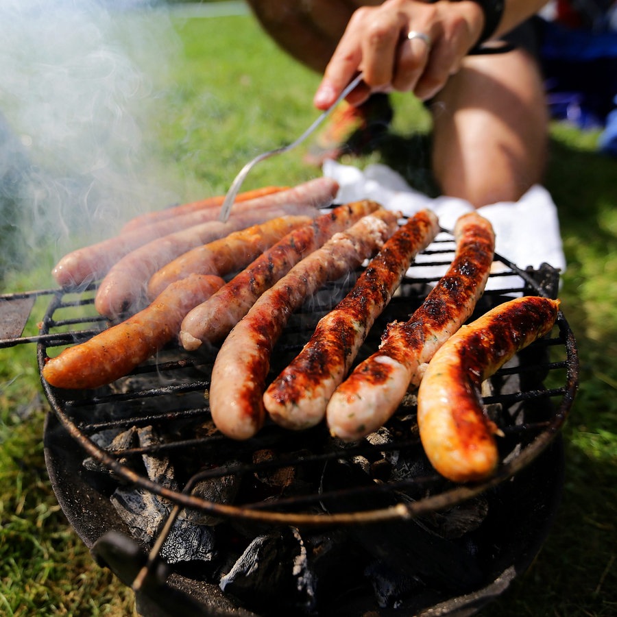 Im Park werden Würstchen auf einem Grill gegrillt. © picture alliance Foto: Ludovic Maillard