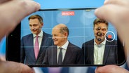 Bundeskanzler Olaf Scholz, Robert Habeck, und Christian Lindner nehmen an einer Pressekonferenz zum Haushaltsplan 2025 teil. © picture alliance Foto: Kay Nietfeld