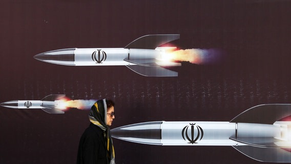 Eine Frau spaziert am 19.4. in Teheran vor einem Plakat mit Raketen. © picture alliance Foto: Fatemeh Bahrami