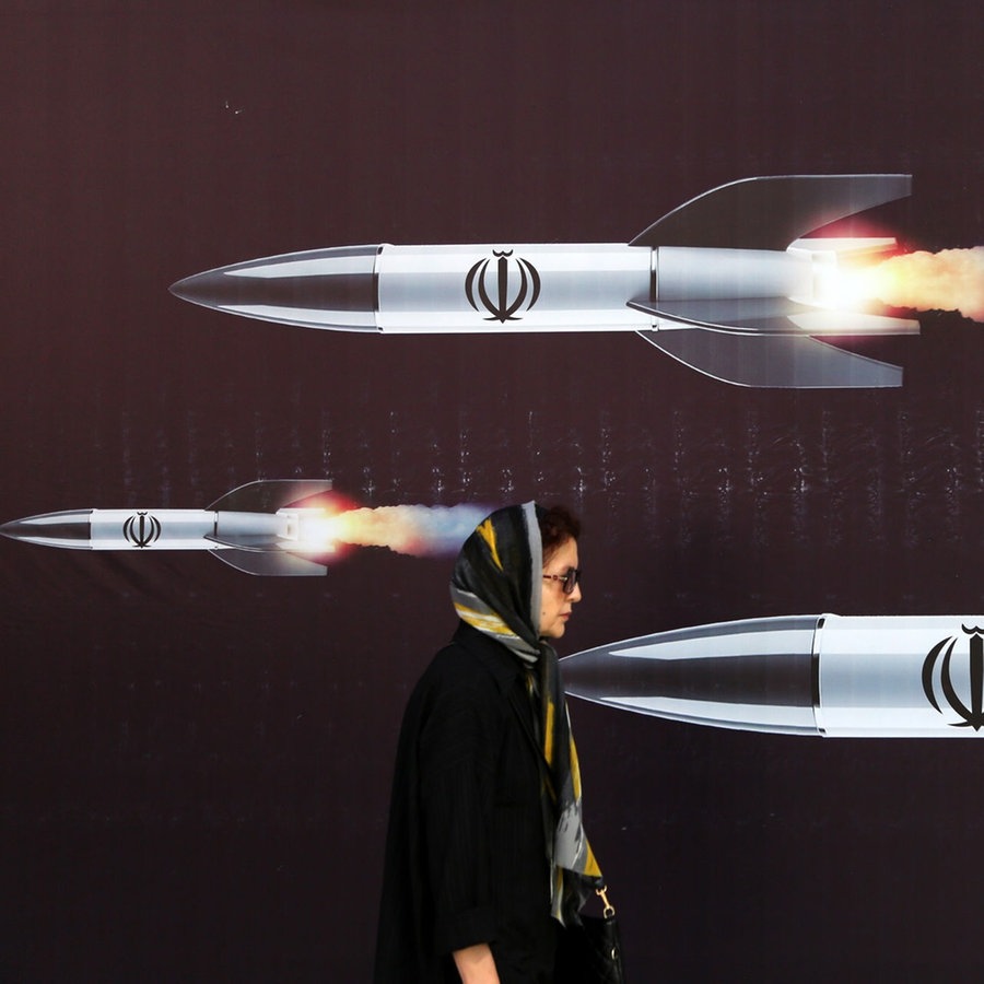 Eine Frau spaziert am 19.4. in Teheran vor einem Plakat mit Raketen. © picture alliance Foto: Fatemeh Bahrami