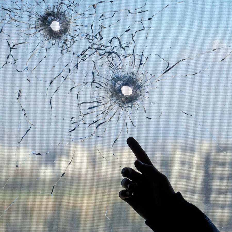 Jemand zeigt auf Einschusslöcher in einem Fenster in der Stadt Jableh in der Provinz Latakia im Nordwesten Syriens. © AP/dpa Foto: Omar Albam