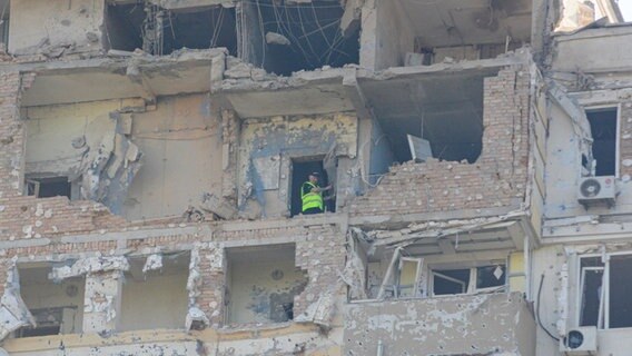 Ein Mann steht in einem Gebäude, das bei dem dritten russischen Luftangriff auf die ukrainische Hauptstadt innerhalb der letzten 24 Stunden stark beschädigt wurden. © dpa-Bildfunk Foto:  Aleksandr Gusev
