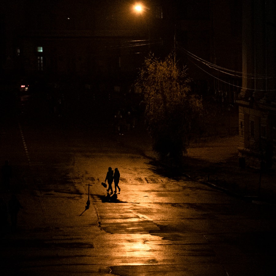 Menschen laufen nachts während einer Stromsperre in Kiew über eine Straße. © Andrew Kravchenko Foto: AP/dpa