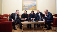 Der Premierminister von Großbritannien, Keir Starmer, der Präsident der Ukraine, Wolodymyr Selenskyj, Frankreichs Präsident Emmanuel Macron, der Ministerpräsident von Polen, Donald Tusk, und Bundeskanzler Friedrich Merz sitzen im Präsidentenpalast in Kiew zusammen an einem Tisch und warten auf den Anruf von US-Präsident Donald Trump. © Ukrainisches Präsidentenbüro/dpa 