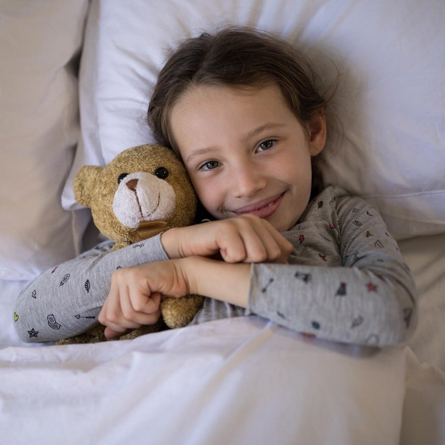 Ein Kind liegt mit einem Teddy im Arm im Bett © picture alliance / Zoonar | Channel Partners Foto:  Channel Partners