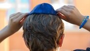 Ein Junge setzt sich eine Kippa auf den Kopf. © picture alliance / dpa | Daniel Bockwoldt Foto: Daniel Bockwoldt