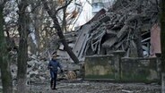 Ein Mann geht an einem Schulgebäude in Kramatorsk (Ukraine) vorbei, das bei einem Angriff schwer beschädigt wurde. © Libkos/AP/dpa Foto: Libkos