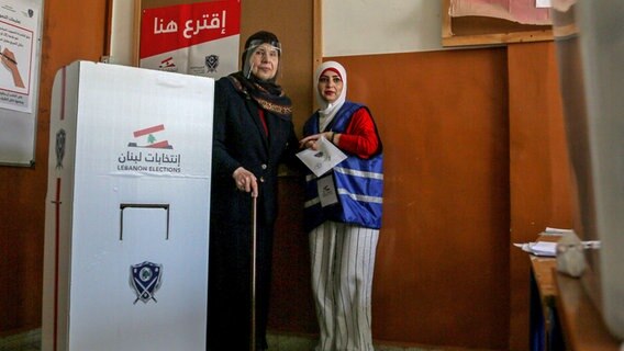 Eine Wählerin wird in einem Wahllokal in einem überwiegend schiitischen Vorort von Beirut bei der Stimmabgabe zur Parlamentswahl im Libanon von einer Wahlhelferin empfangen. © dpa Foto: Marwan Naamani