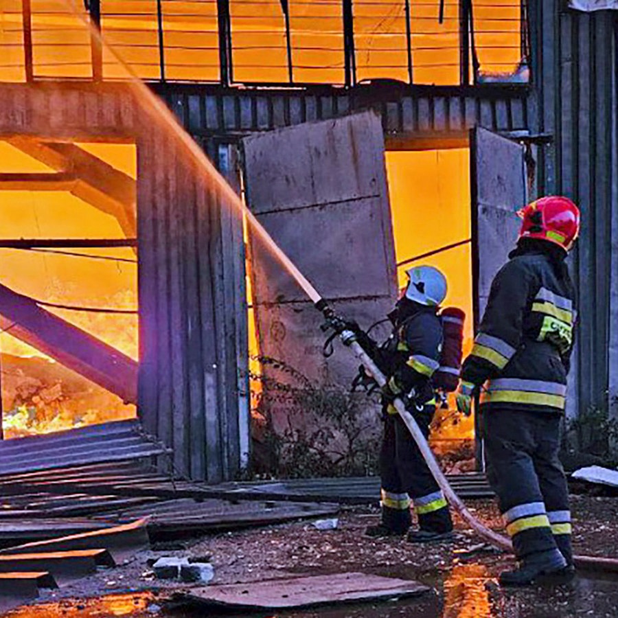 Zwei Rettungskräfte löschen ein Feuer nach einem Drohnenangriff auf die Stadt Lemberg (Lwiw, Ukraine). © Ukrainian Emergency Service/AP/dpa 