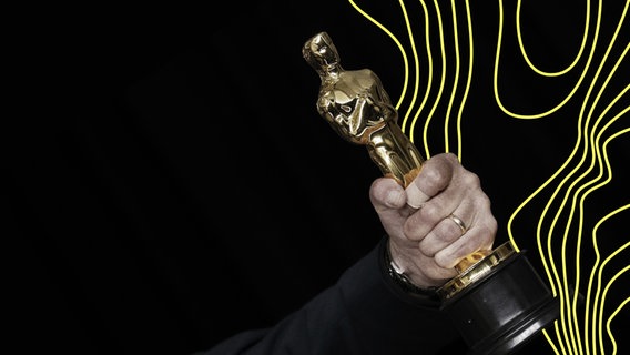 Eine männliche Hand hält einen sogenannten Oscar, einen Filmpreis. © picture alliance Foto: John Angelillo