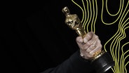 Eine männliche Hand hält einen sogenannten Oscar, einen Filmpreis. © picture alliance Foto: John Angelillo