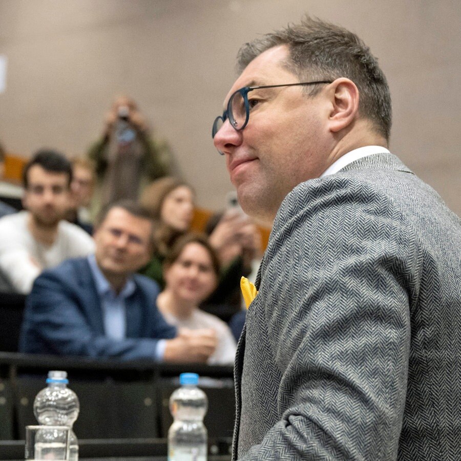 Der Botschafter der Ukraine, Oleksii Makeiev, unterhält sich bei einem Termin an der Universität in Mainz mit Studierenden in einem Hörsaal. © dpa Foto: Boris Roessler
