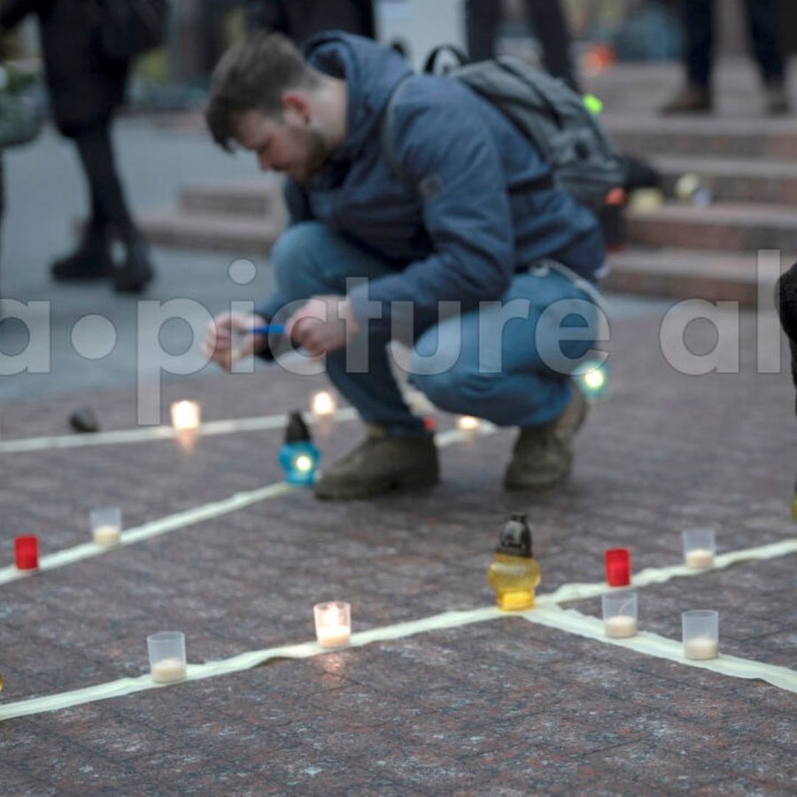 Menschen zünden Kerzen während einer friedlichen Aktion zum Gedenken an die vor einem Jahr im Theater von Mariupol getöteten Menschen an. © picture alliance/dpa/AP | Foto:  Andrew Kravchenko