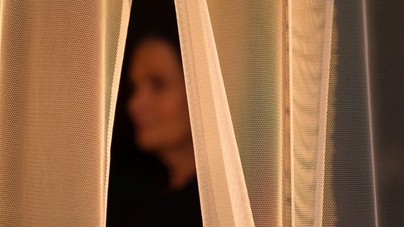 Ein Opfer von sexualisierter Gewalt steht hinter einem Vorhang. © picture alliance/dpa/Ole Spata Foto: Ole Spata