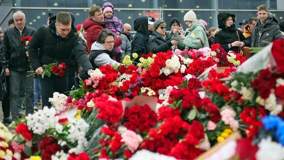 Menschen legen Blumen und Spielzeug am Zaun neben dem Konzertsaal bei Moskau ab, auf den ein Terroranschlag verübt worden war. © Vitaly Smolnikov/AP/dpa 